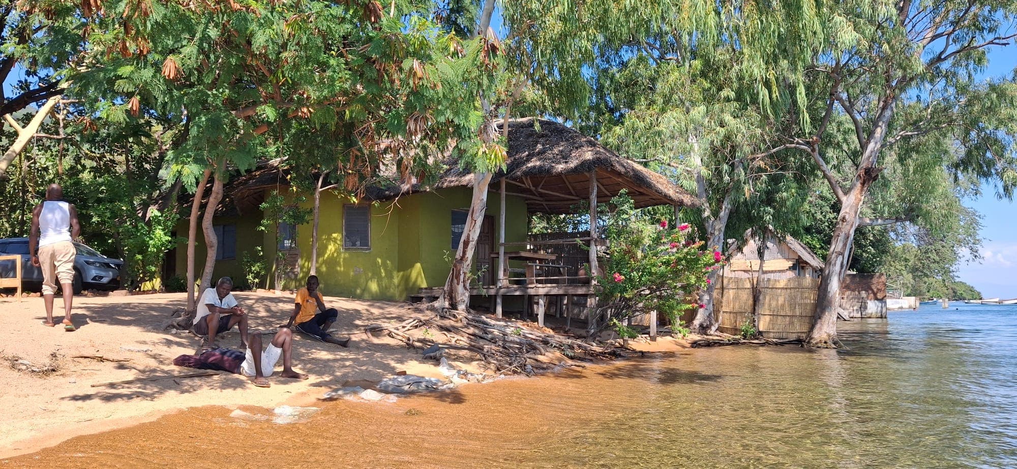 Guests relaxing in the shade along the beach at Cape Maclear